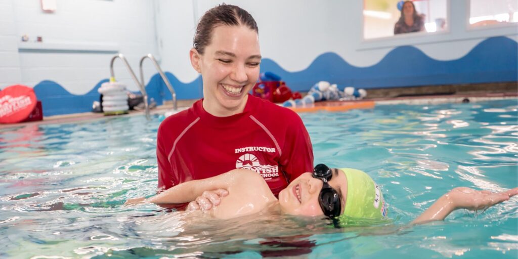 Swim instructor with child teaching him how to swim