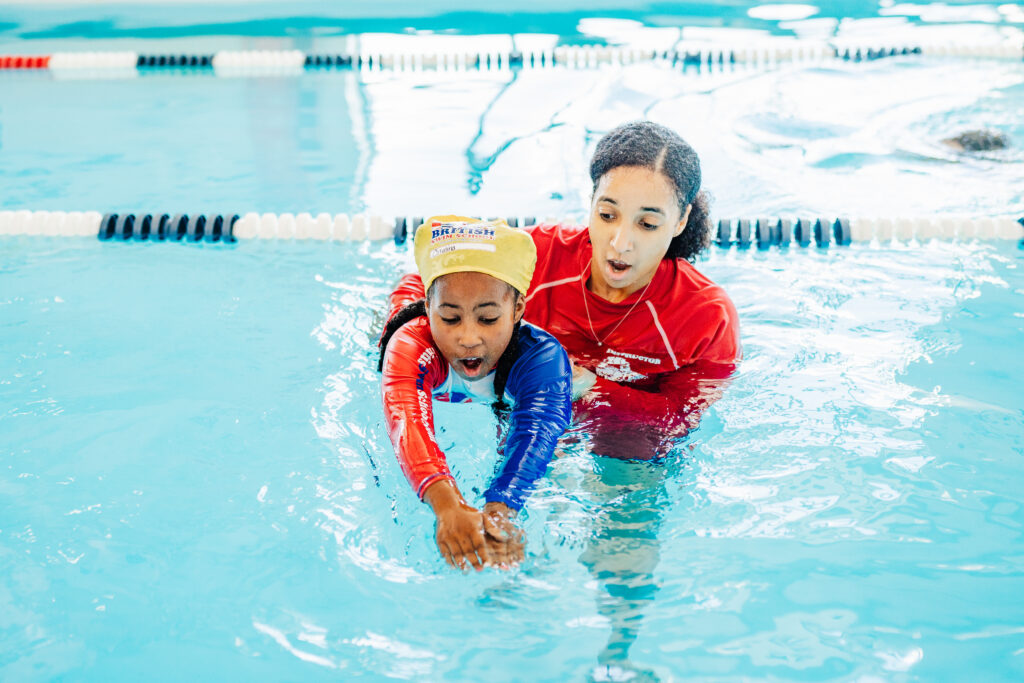 British Swim School instructor guiding a young child through a swim drill at British Swim School of Austin.