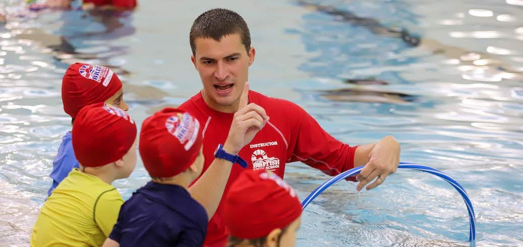 Monitor de natación dando una clase de natación a varios niños