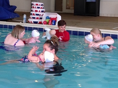 Babies learning to swim with their mothers and swim instructor