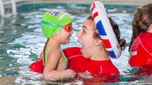 Instructor with swim ring on head laughing with child