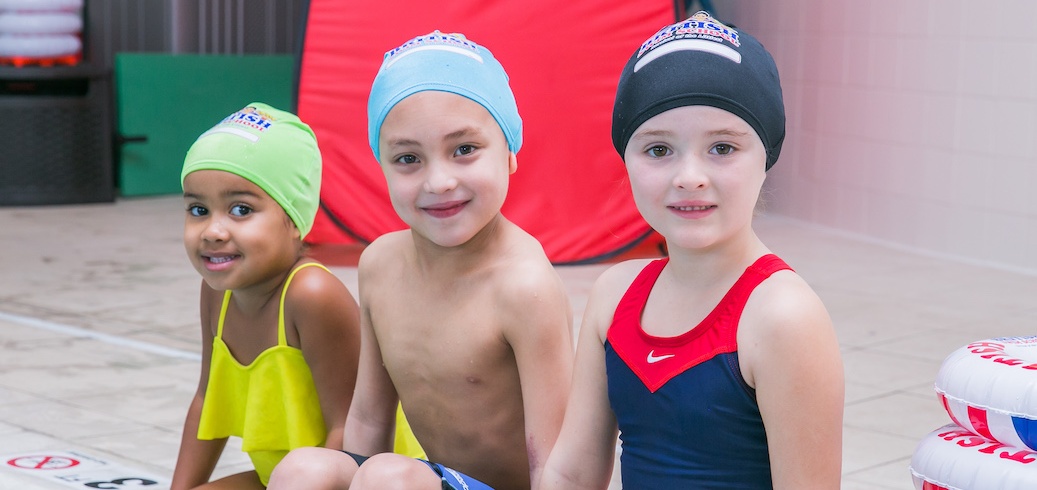 Three children taking a swimming class for kids