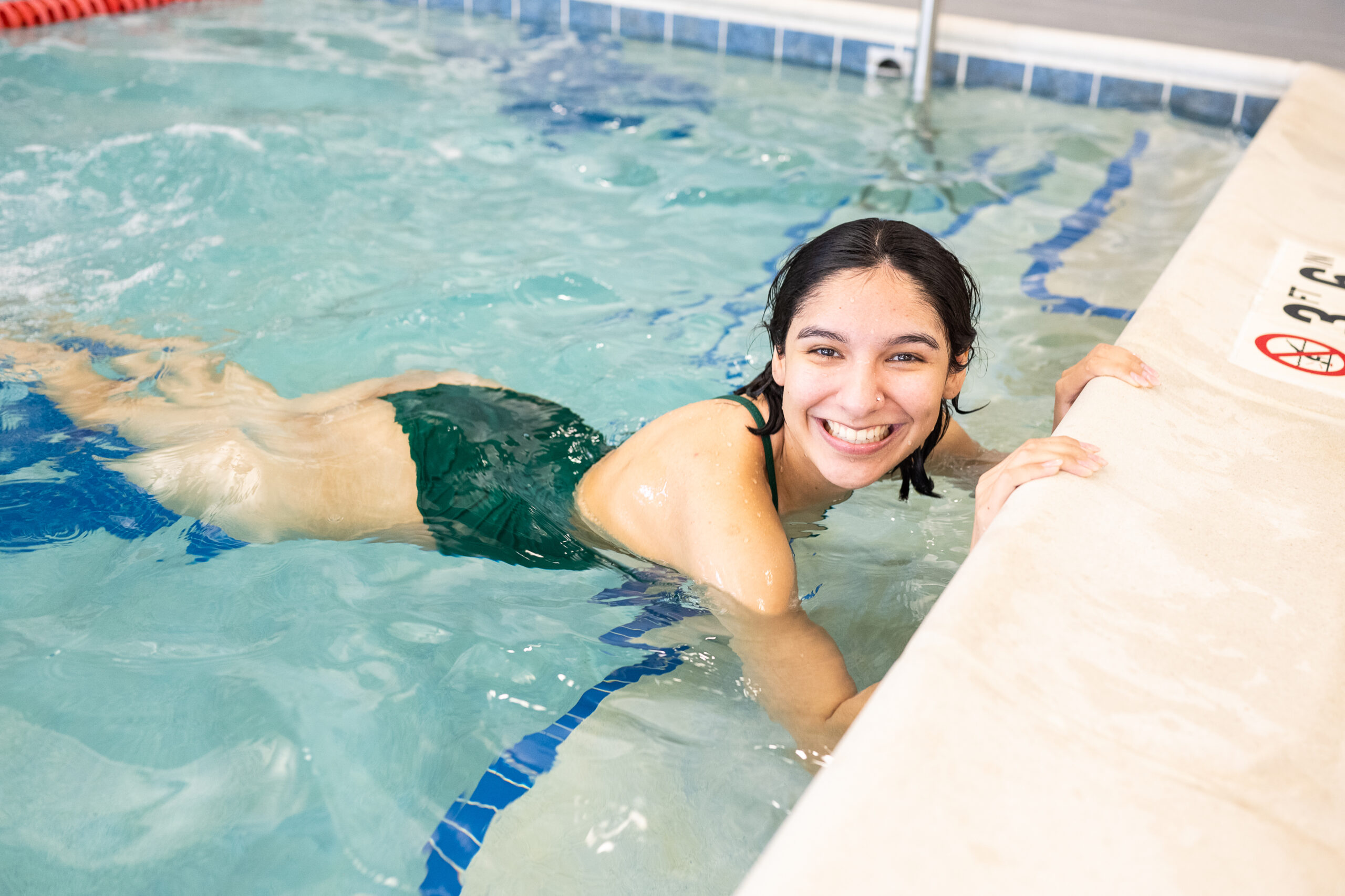 Adult swimmer smiling in indoor pool during swim lessons at British Swim School.