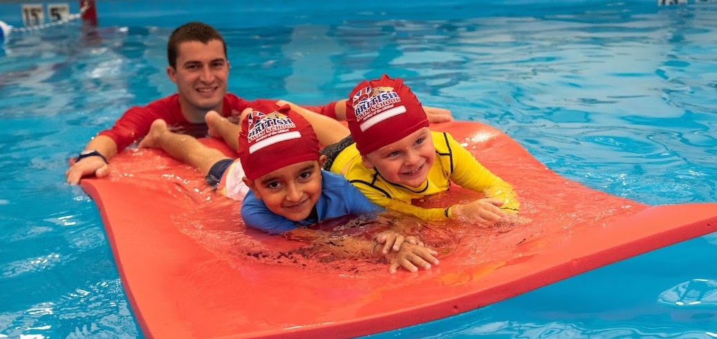 Two swim students floating with a British Swim School Instructor