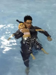 Child floating in the pool with a swim instructor
