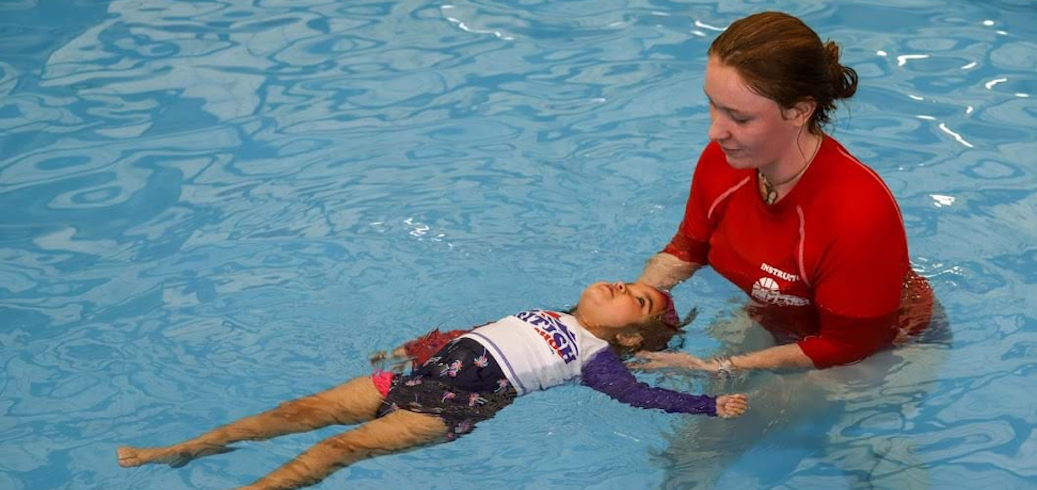 Swim instructor teaching swim student to float