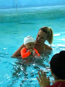 Infant in the pool with mom and swim instructor