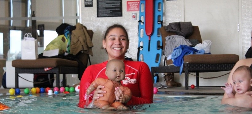 Swim instructor teaching in the pool with a baby doll