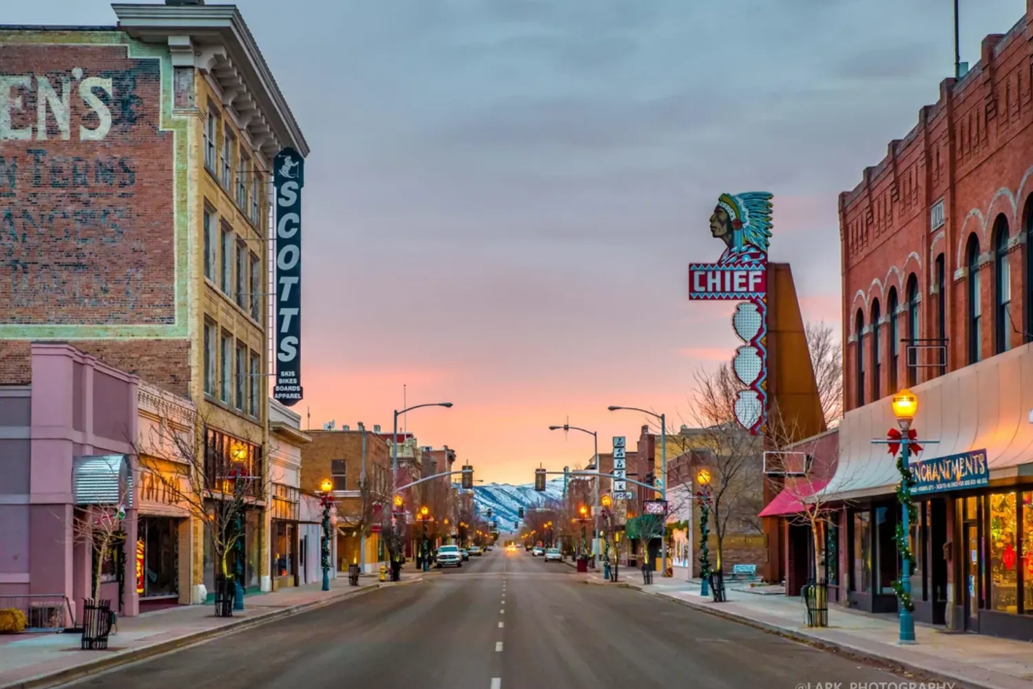Historic downtown street at sunset, featuring old brick buildings, a Chief neon sign, and