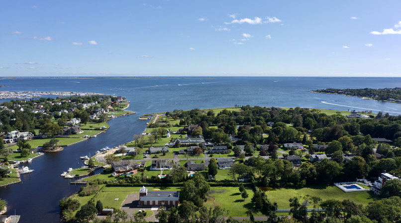 Aerial view of a vibrant coastal community with homes, boats, and a winding river flowing into a