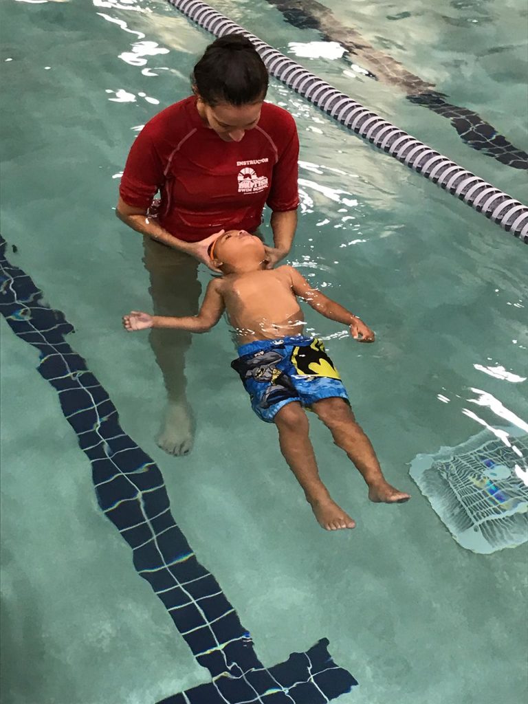 Baby floating in pool with a swim instructor