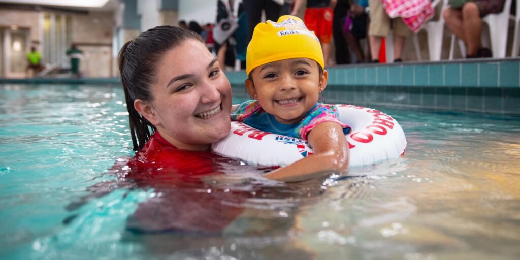 Swim instructor teaching a toddler how to swim