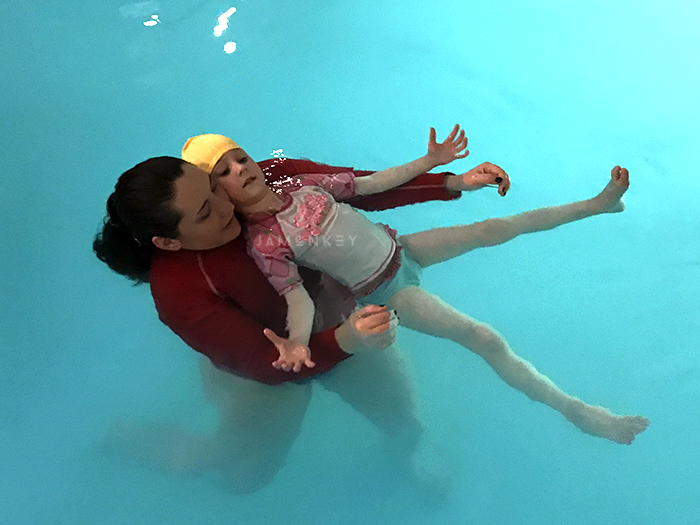 Young woman floating on her back with a swim instructor