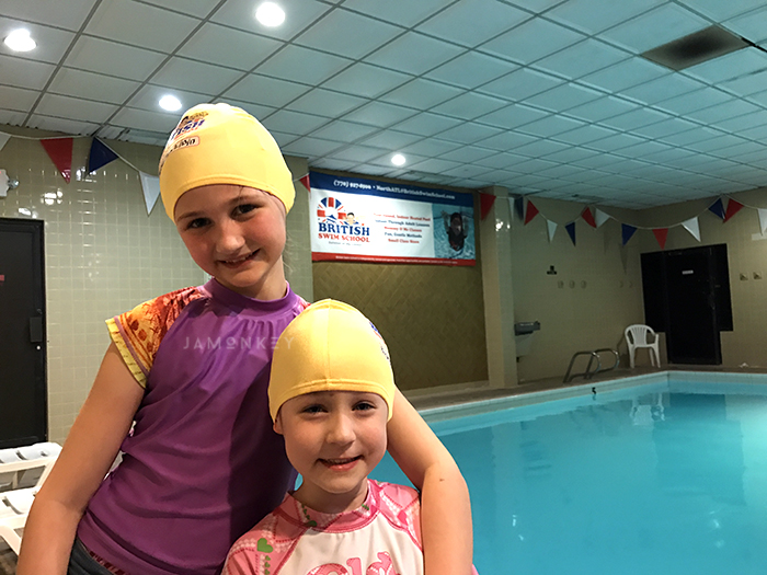 Young women in swim caps standing near the pool