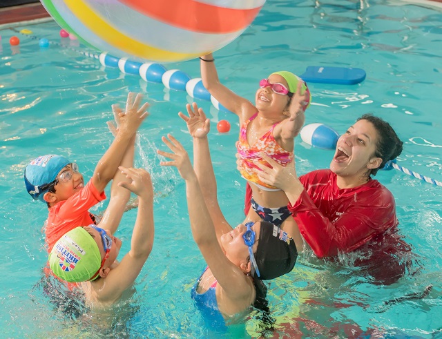 Swim instructor and four children playing in the pool