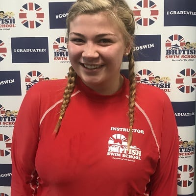 Grace smiling in front of a British Swim School backdrop