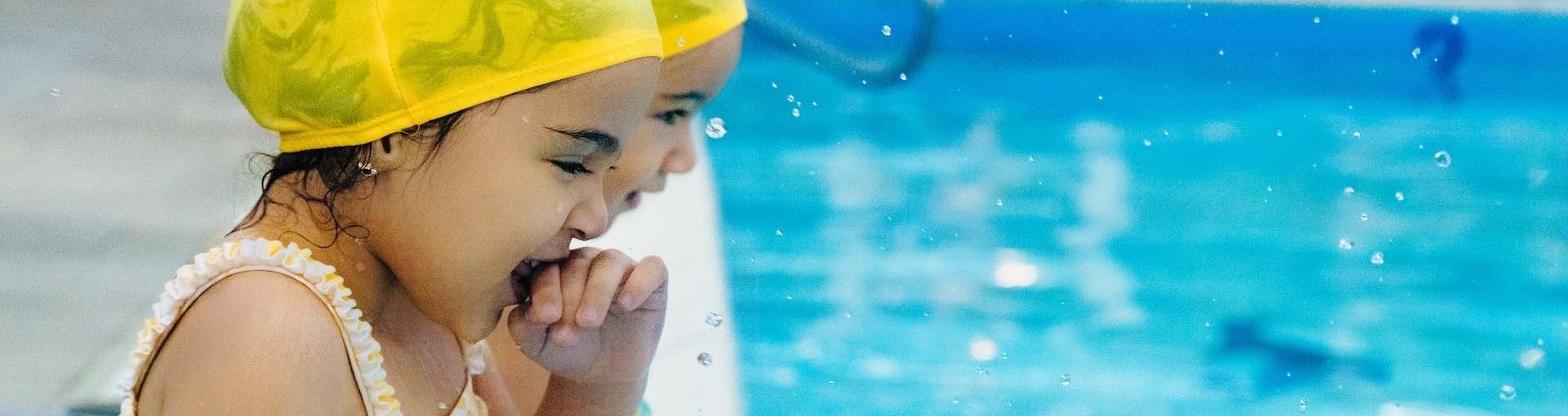 Two Girls on Edge of Pool Taking Swimming Lessons - British Swim School