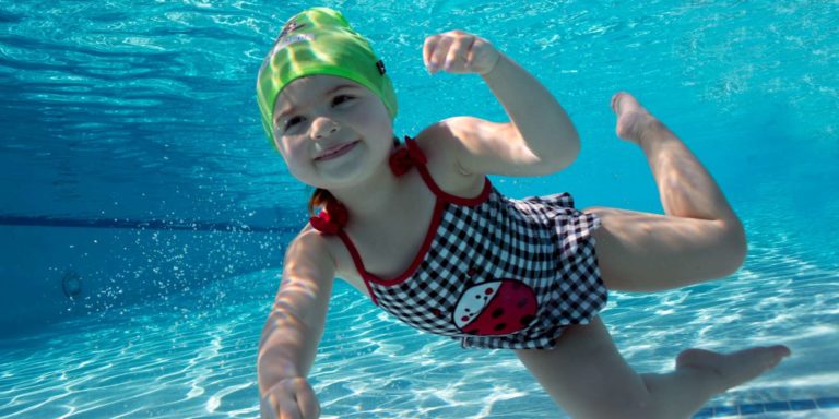 Little girl swimming underwater with swim cap