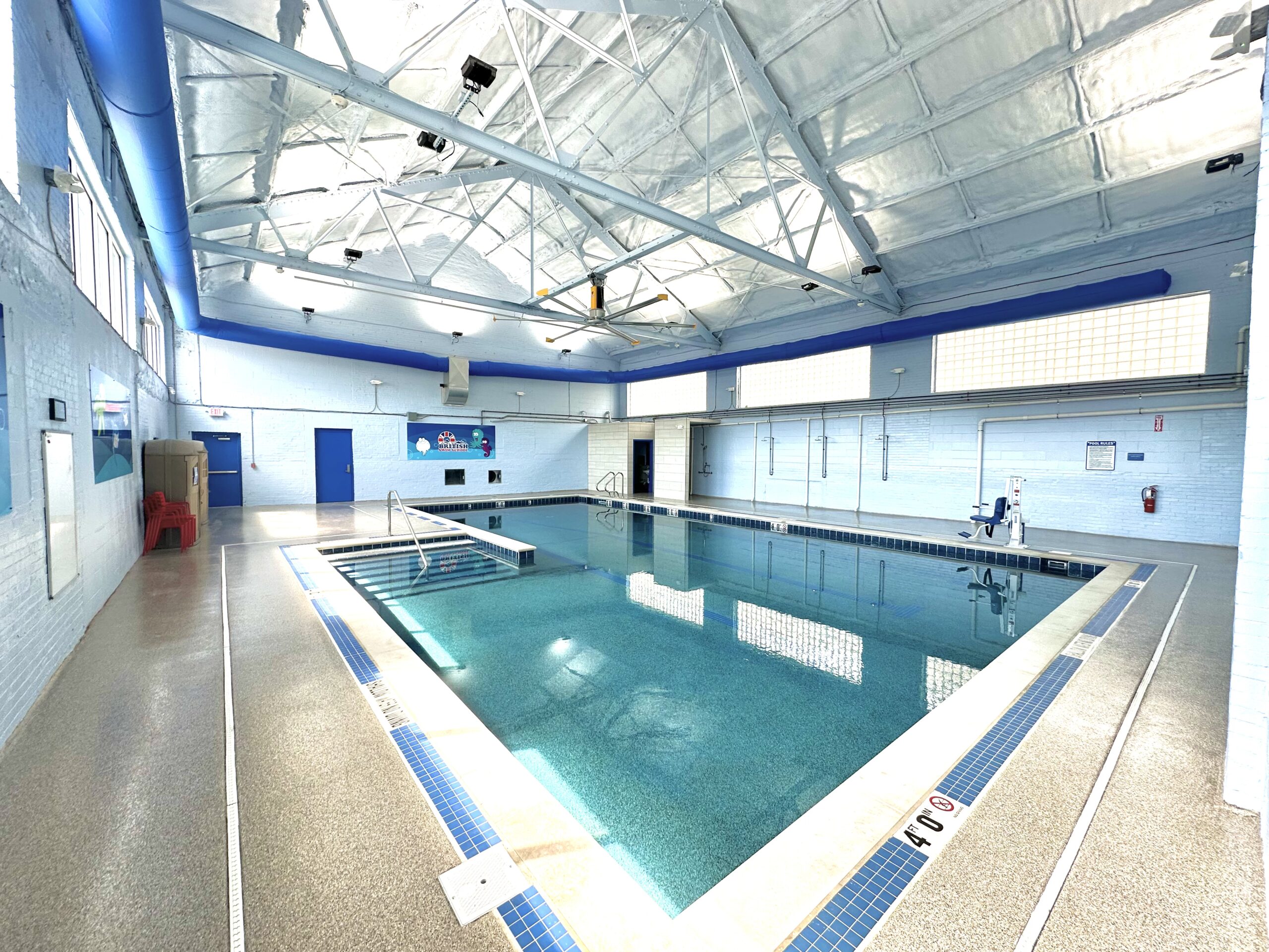 A well-maintained indoor swimming pool with blue accents, a shallow end, and a