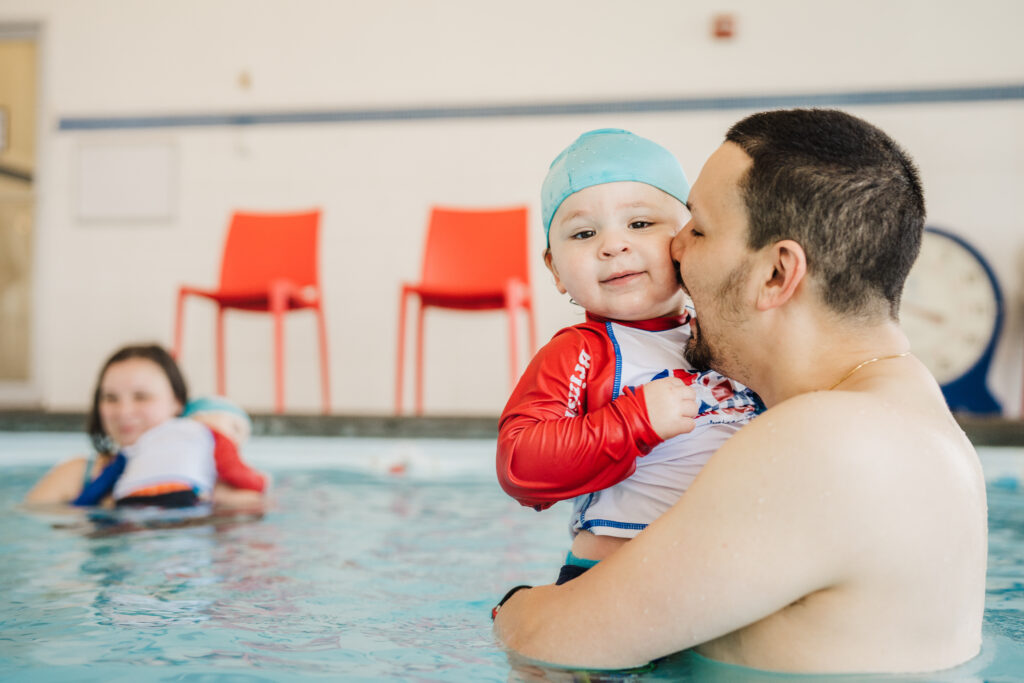 Parent holding a baby during swim lessons at British Swim School.