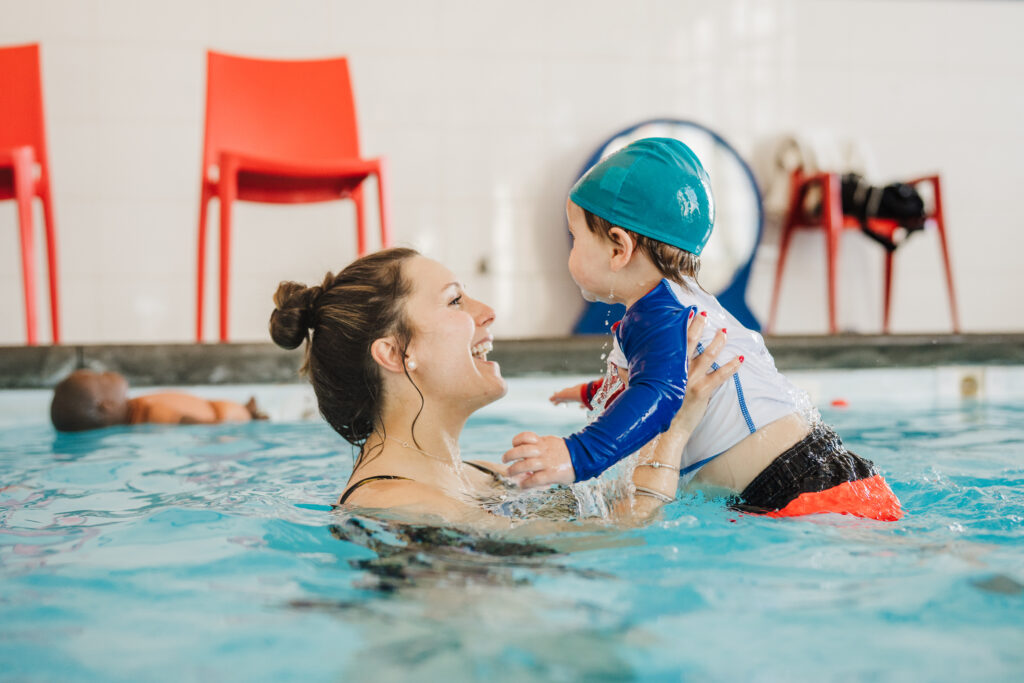 Parent and child smiling together in the pool during a swimming lesson at British Swim School of Tri-Cities-Langley.