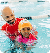 An instructor guiding a smiling child across the pool