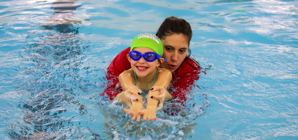 Swim instructor teaching a student about the four. main swimming strokes