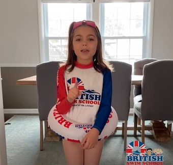 Young girl wearing a British Swim School rash guard and swim ring